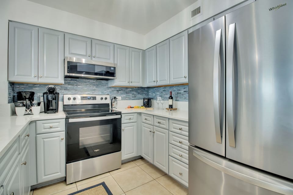Your fully equipped kitchen features stainless steel appliances and coastal-inspired backsplash, perfect for preparing meals during your stay.