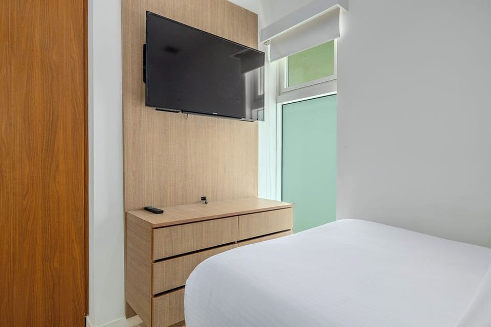 Unwind in your modern bedroom featuring crisp linens, convenient storage, and entertainment at your fingertips.