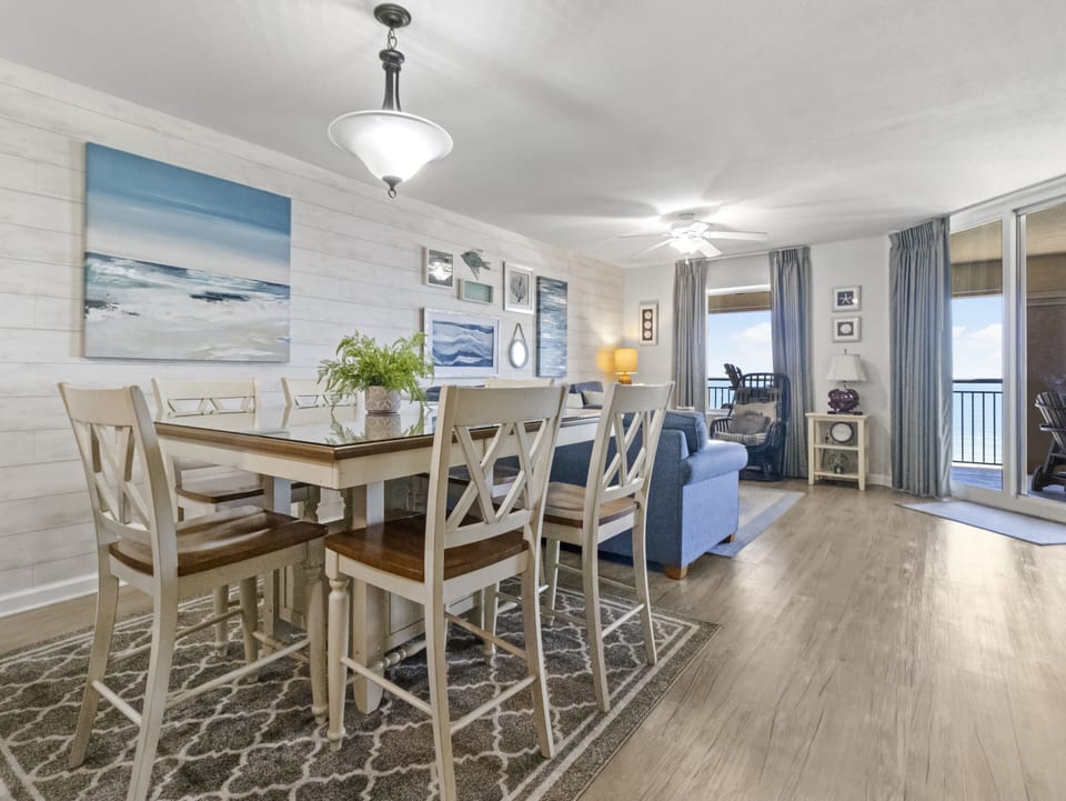 Relax in your coastal-themed dining space where ocean artwork and soft blue tones create a serene atmosphere for memorable meals together.