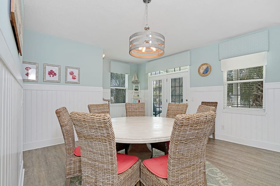 Gather around your beautiful dining table where coastal charm meets comfort in soft blue tones and natural wicker seating.