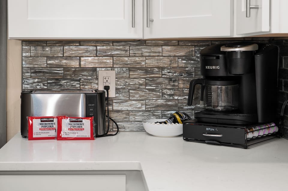 Modern kitchen coffee station with Keurig, toaster, and guest snacks