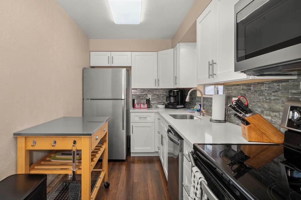 Modern galley kitchen with stainless appliances and handy prep cart