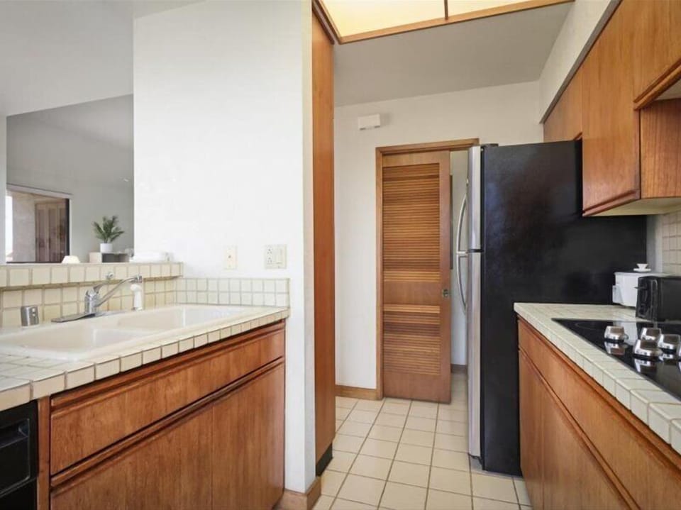 Your fully equipped kitchen features warm wood cabinetry, tiled countertops, and modern appliances—everything you need to prepare meals and feel right at home during your stay.