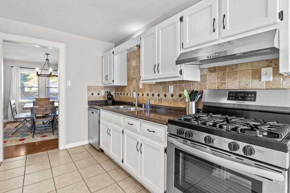 Classic Craftsman-style kitchen with stainless steel appliances, gas range, and tile backsplash—fully equipped for both short- and long-term stays.