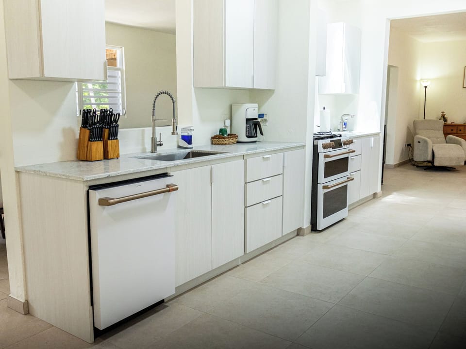 Galley kitchen equipped with stove, refrigerator and dishwasher.