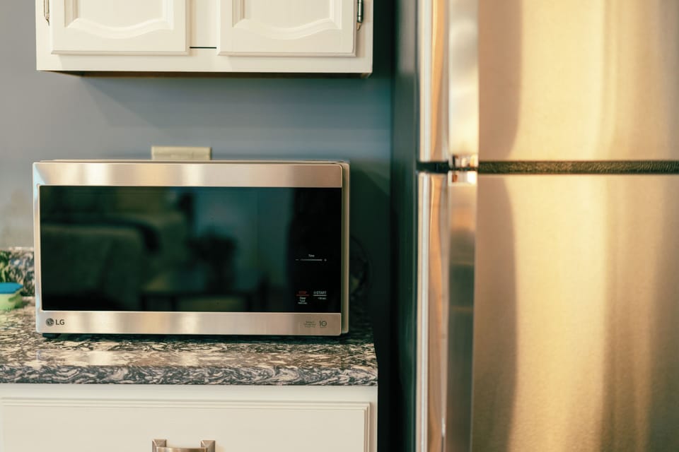 Powerful microwave sits next to a full size refridgerator with freezer over top.