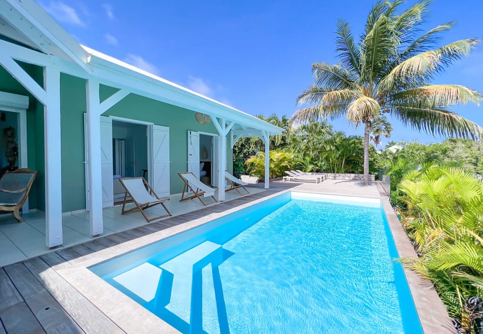 Discover our magnificent upscale villa in the West Indies. Enjoy breathtaking views of the sparkling pool, wooden terrace and rooms bathed in natural light. Let yourself be seduced by the charm of this oasis of tranquility, where you can relax on deckchairs while admiring the surrounding beauty. Book now and treat yourself to an unforgettable vacation.