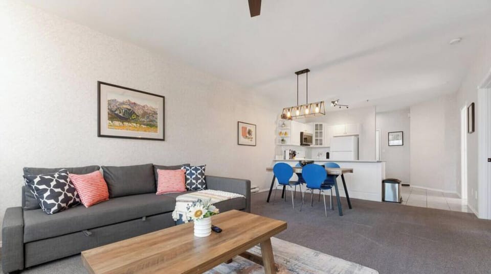Living room with a Smart TV, walkout access to the private balcony, an air-conditioning unit in the window and a cozy couch with a pull-out sleeper sofa (all bedding provided.)