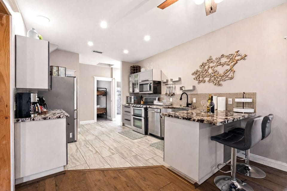 Sleek Open Kitchen with Granite Breakfast Bar & Stainless Steel Appliances | Bright, Modern Layout with Bar Seating, Coffee Station & Spacious Prep Area | Fully Equipped for Cooking, Gathering & Comfortable Extended Stays

