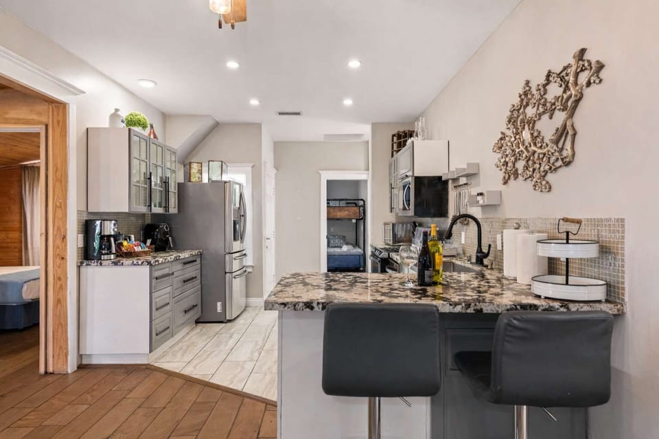 Bright Modern Kitchen with Granite Island & Stainless Appliances | Open Layout, Coffee Station, Bar Seating & Seamless Flow to Living Area | Clean, Fully Equipped Space Perfect for Cooking, Entertaining & Relaxed Guest Stays