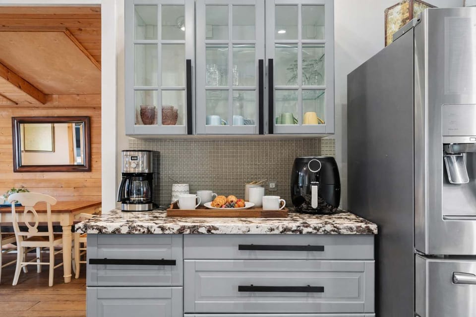 Stylish Coffee & Breakfast Station with Granite Counters | Glass Cabinets, Espresso Machine & Stainless Fridge | Thoughtfully Designed Nook for Morning Coffee, Snacks & Easy Access to Dining Area
