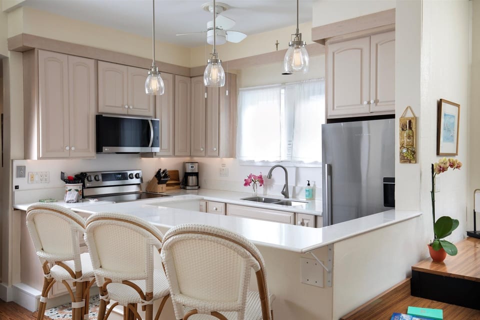 Upgraded kitchen appliances and eat up counter with stools.