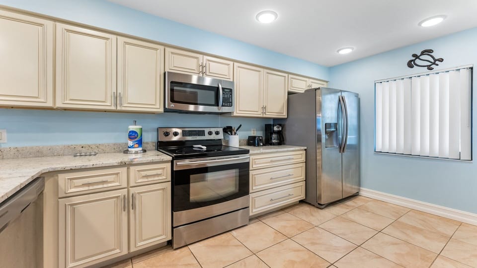 Kitchen with complete amenities like microwave oven, refrigerator, coffee maker and oven.