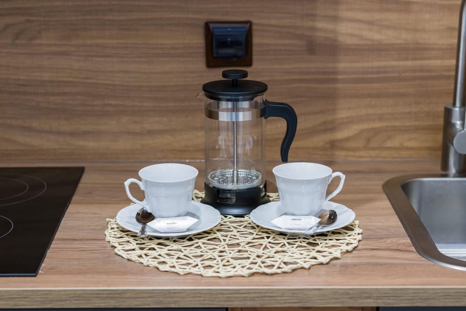 A tray set with a coffee pot, cups, and a cozy touch, perfect for enjoying a morning brew.
