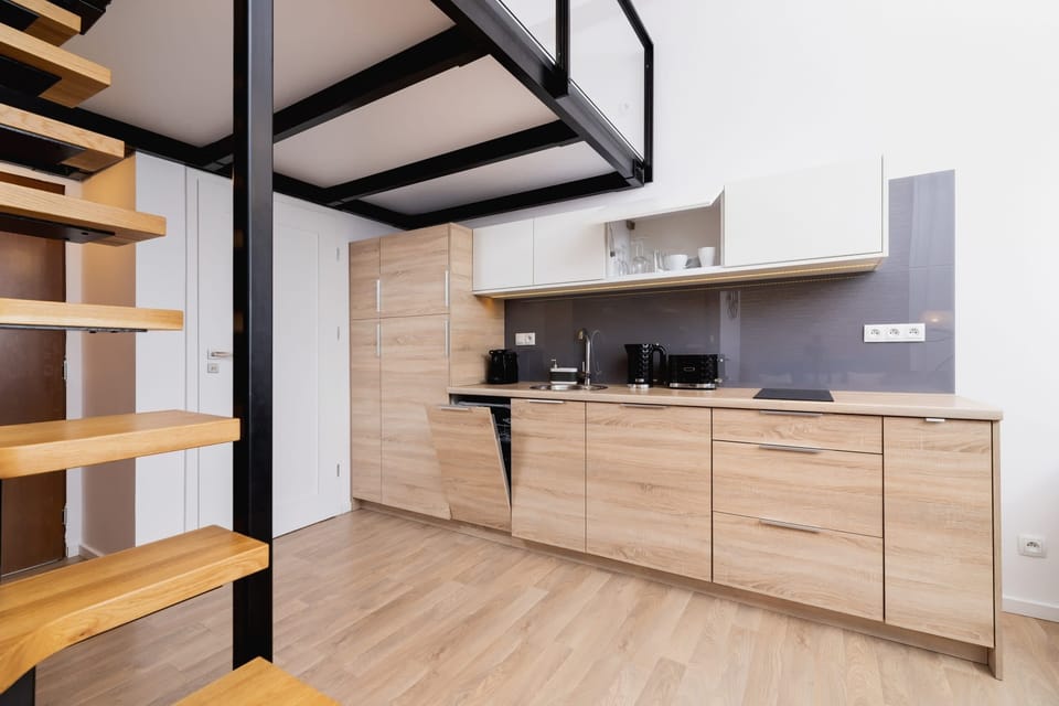 A modern kitchen showcasing wooden cabinets and black hardware. Ample countertop space and overhead lighting make it ideal for cooking and entertaining.