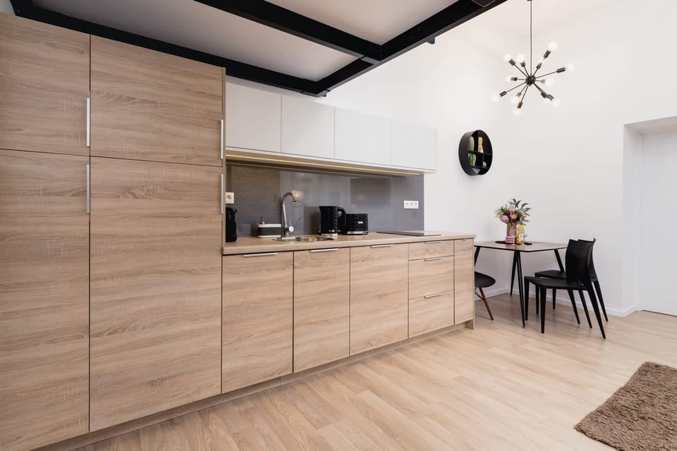 A compact kitchen with bright lighting and a spacious countertop. Open shelving displays neatly arranged dishes for easy access.