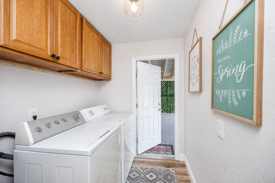 Hallway laundry with washer, dryer, supplies, and extra beach towels.