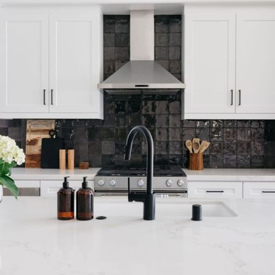 Stylish kitchen w/ stainless range, vent hood & textured tile backsplash