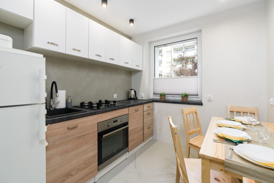 A modern kitchen with white cabinets, wooden lower cabinets, and a dining area for four.
