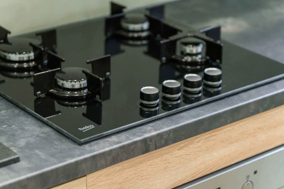 A close-up of a sleek black gas stove with a minimalist countertop.
