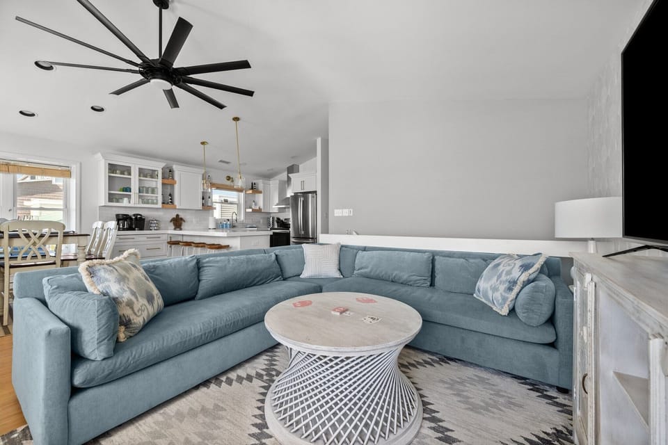 The living area is open to the dining area and kitchen, and features a new West Elm sectional, two comfy swivel chairs, and a large smart TV.