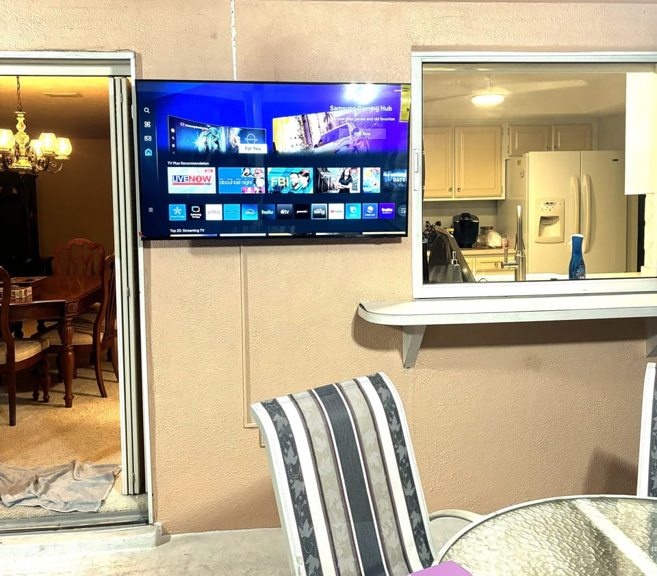 New tv mounted in lanai between sliding glass door and pass-thru to kitchen.