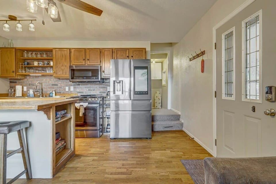 Cook and connect in the warm kitchen—wood cabinetry, stainless fridge, and an island with seating so someone can snack, chat, or keep you company while dinner comes together.