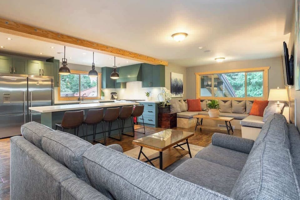 - Spacious living area blending modern comfort with mountain lodge style  
- Open layout connects kitchen, bar seating, and lounge for easy gatherings  
- Relax with forest views, soft lighting, and cozy sectional after exploring  
