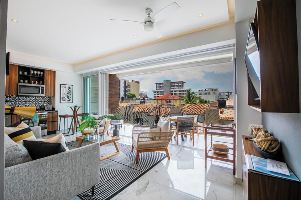 Step into your bright, open living space where indoor comfort meets outdoor charm. The inviting seating area flows seamlessly onto a furnished terrace, perfect for morning coffee or evening relaxation while enjoying the surrounding cityscape.