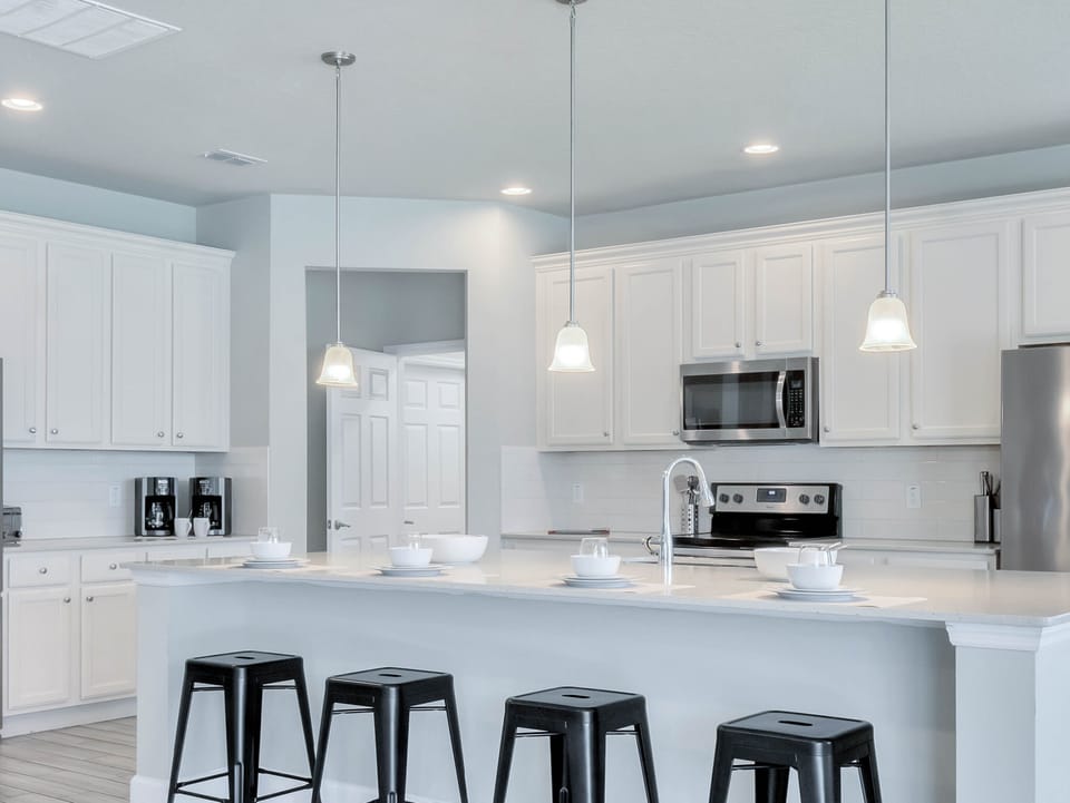 - White kitchen with pendant lighting and stools  
- Stainless appliances in vacation rental home  
- Spacious Orlando kitchen for family cooking