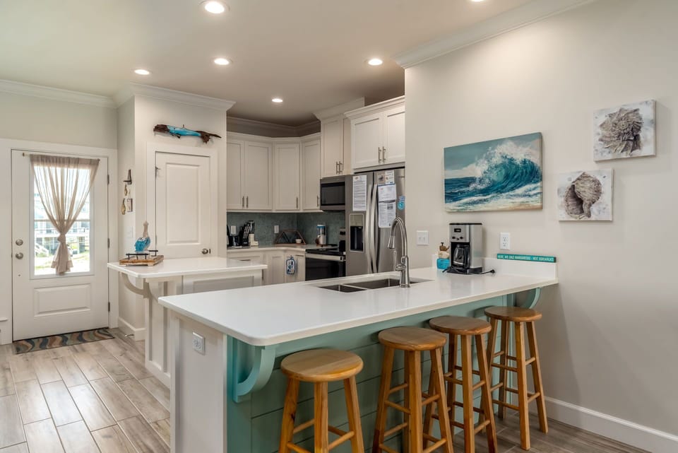 Your spacious kitchen invites culinary adventures with modern appliances, coastal artwork, and a perfect breakfast bar for morning coffee.