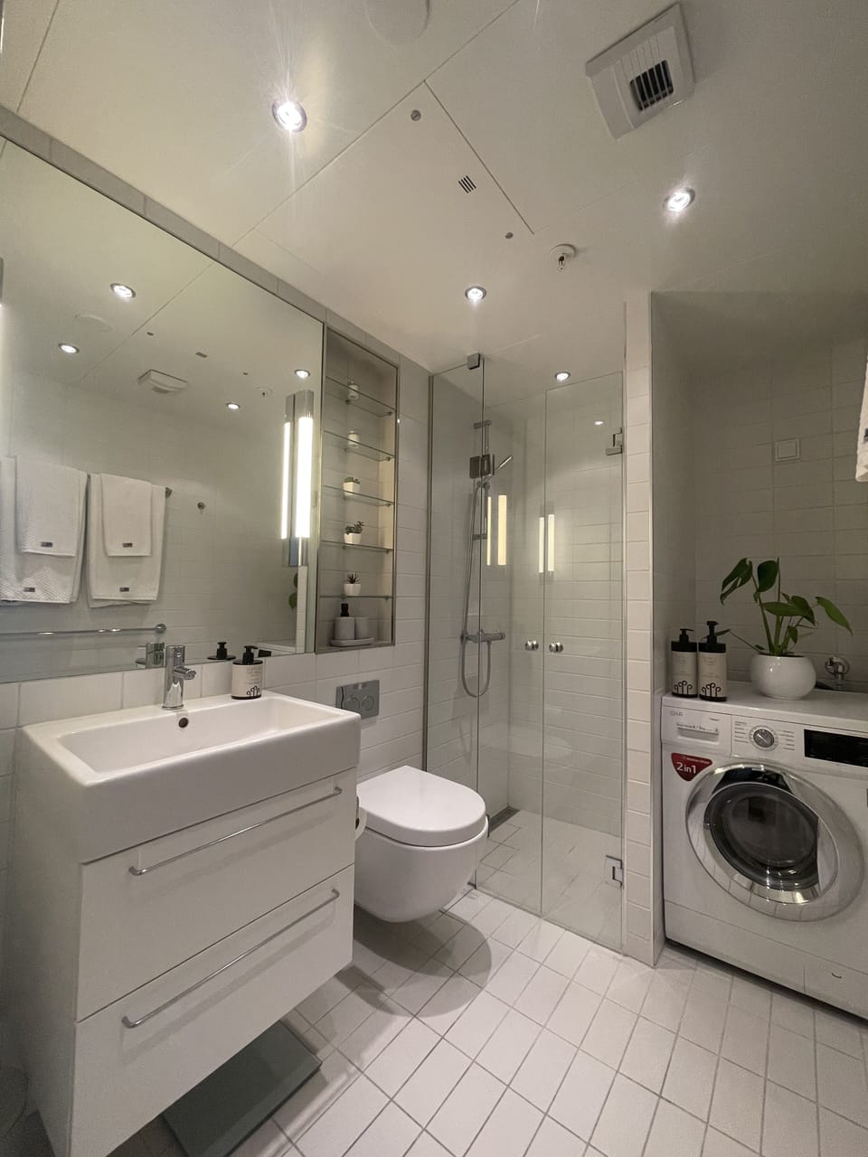 Modern bathroom with walk-in shower and washer.