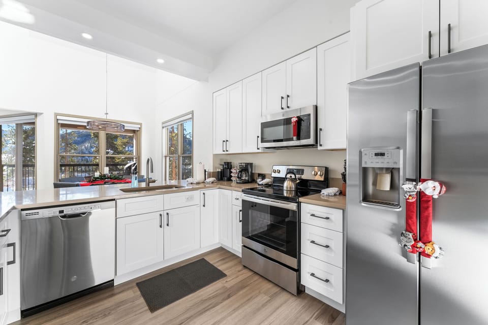 Your fully-equipped kitchen features stainless steel appliances and bright windows overlooking the mountains, perfect for preparing meals.
