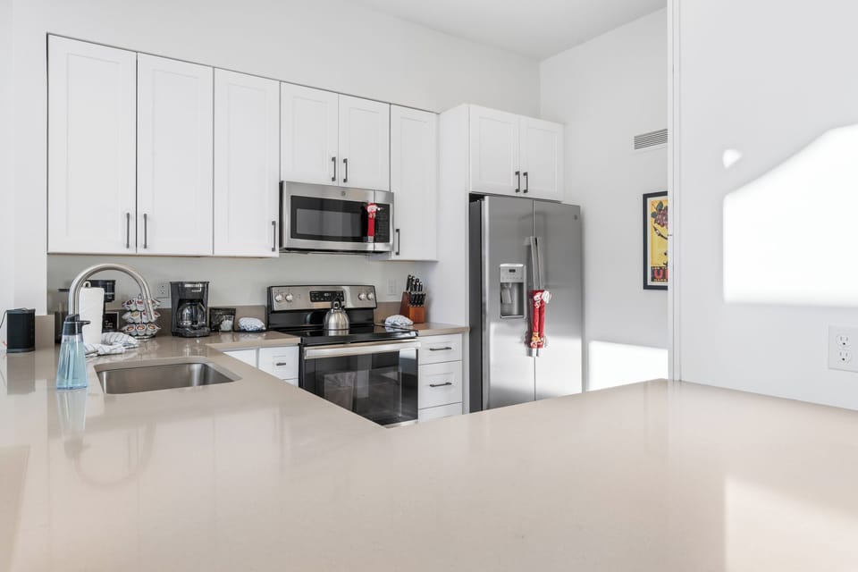 Your sleek modern kitchen features stainless steel appliances and bright countertops perfect for preparing morning coffee or evening meals.