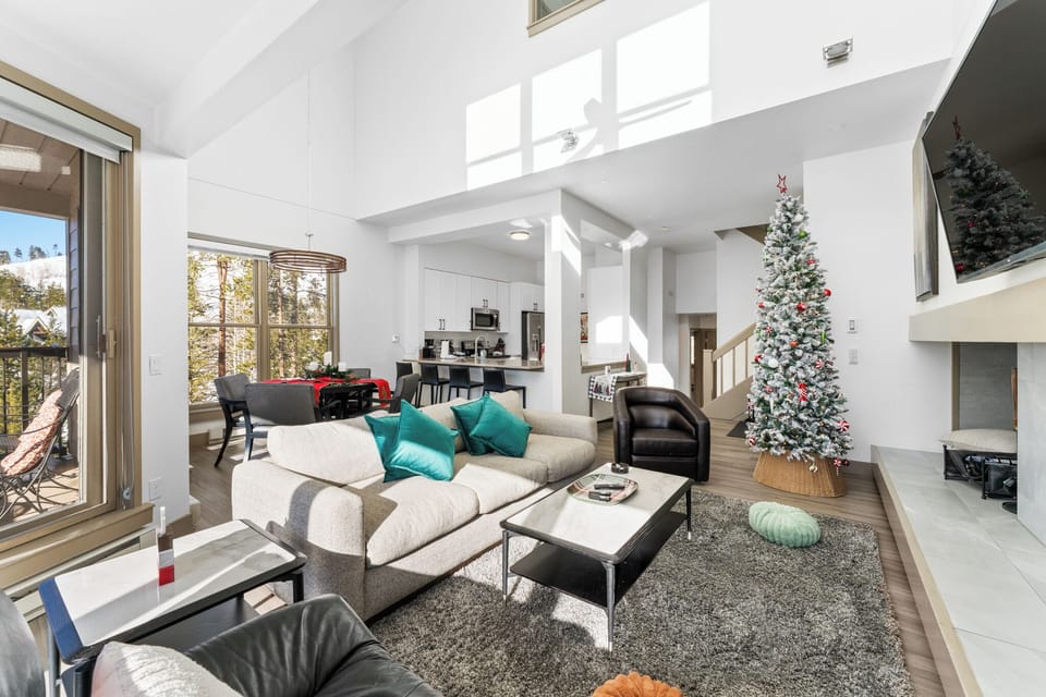 Relax in this bright open-concept living space with soaring ceilings, cozy seating, and festive holiday decorations creating the perfect home-away-from-home atmosphere.