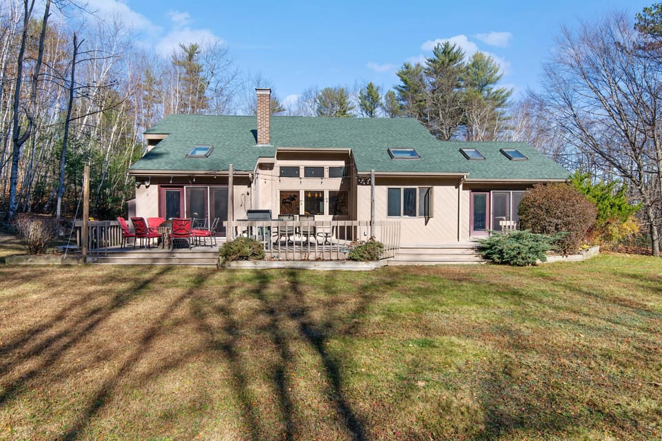 Large backyard, large deck, gas grille, fire pit, patio set and string lights.