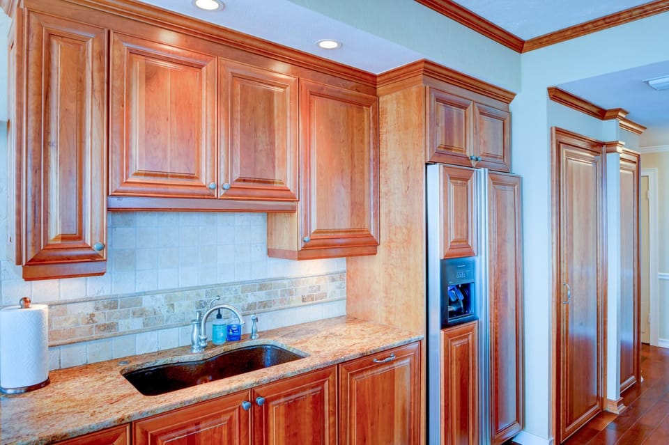 Under-cabinet lighting highlights the tile backsplash and granite countertop with an inset dark sink in the kitchen.