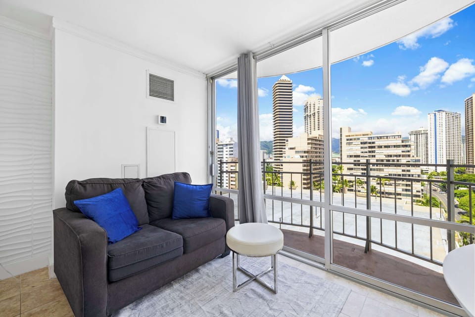 Gray sofa with chic decor, and expansive floor-to-ceiling windows showcasing city views 
