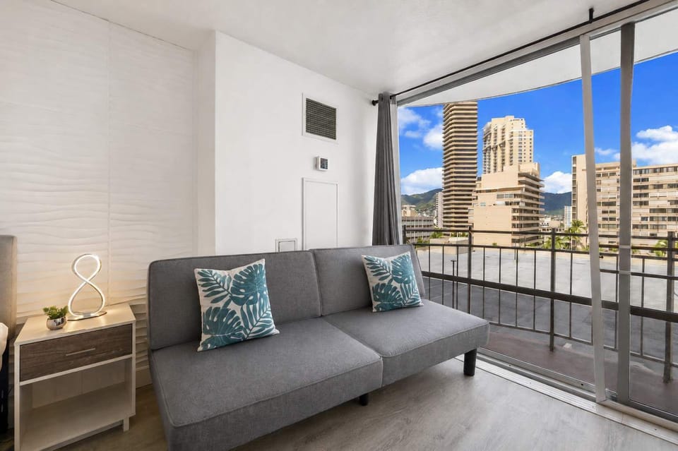 Gray sofa with chic decor, and expansive floor-to-ceiling windows showcasing city views 
