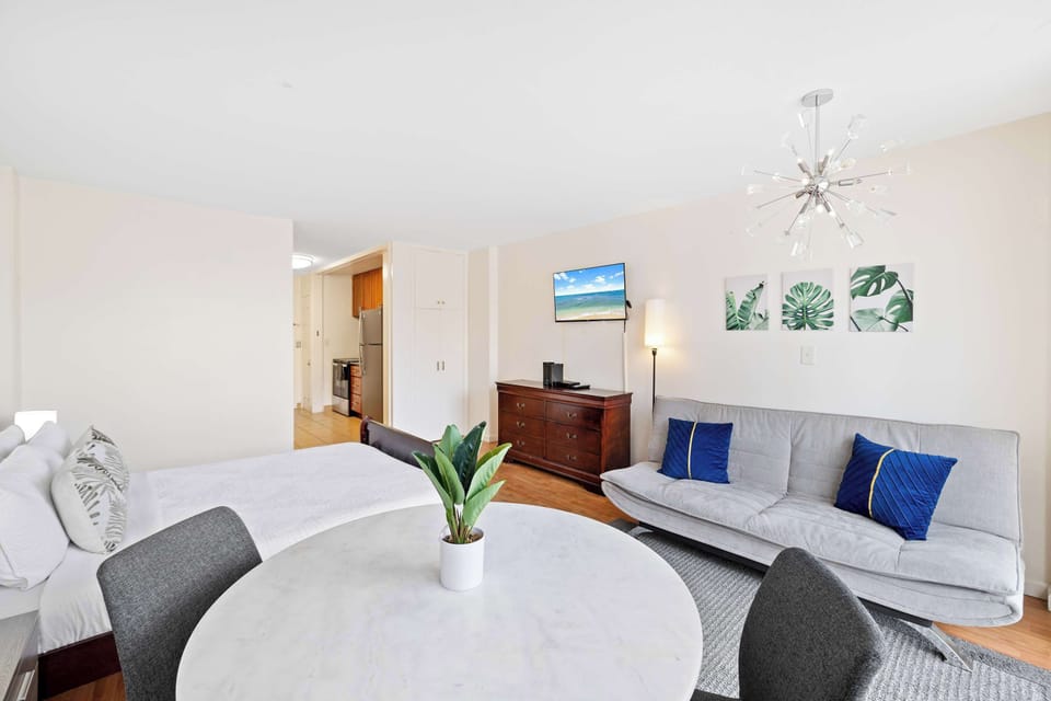 Bright studio with a queen bed, sofa, and a cute table