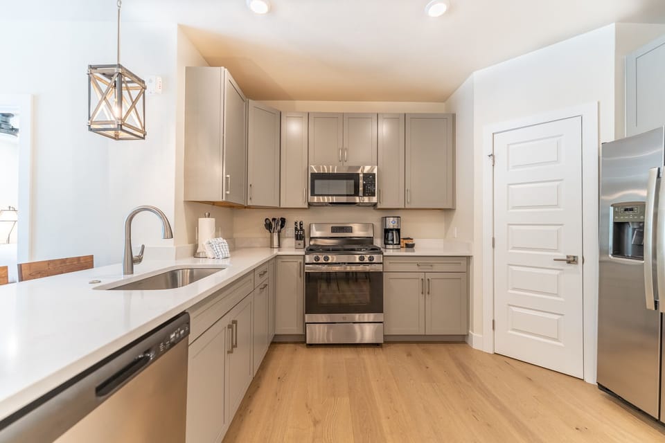 Your modern kitchen features sleek gray cabinets, stainless steel appliances, and quartz countertops for all your cooking adventures.