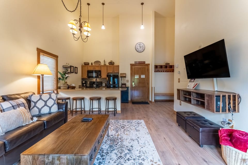 Relax in your spacious open-plan living space with comfortable seating, modern kitchen, and entertainment center perfect for unwinding after mountain adventures.