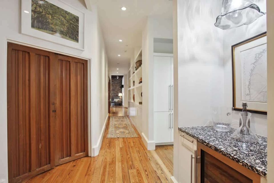 To the right in this photo you see the bar which includes a beverage fridge and pull out shelves for glasses. The vintage double-wood-doors lead the the laundry room. Down this hallway is the Game Room.