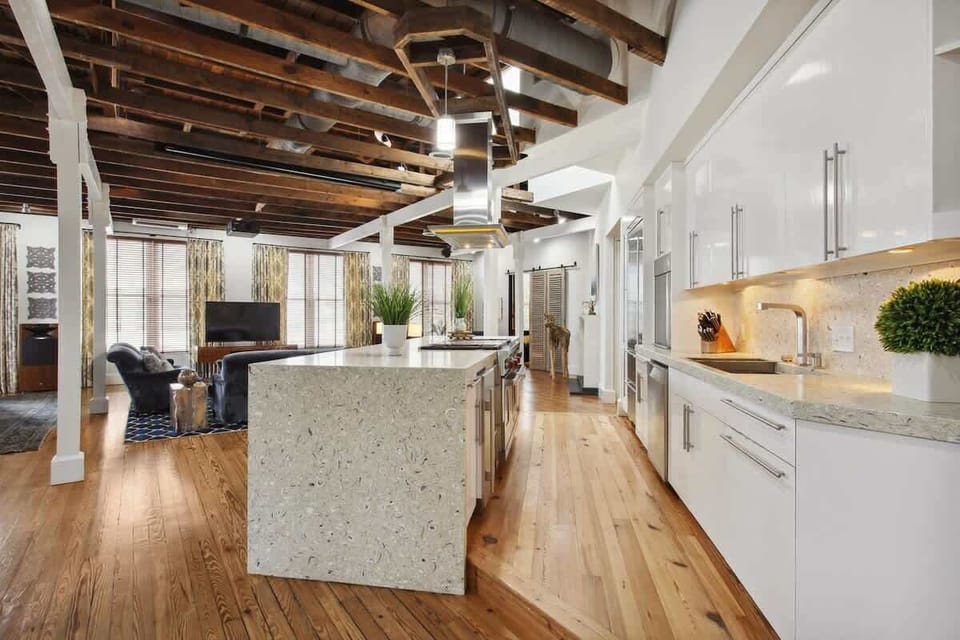 Raised Kitchen overlooks expansive living space and dining areas. With exposed beams overhead, a plethora of windows and heart-pine floors!