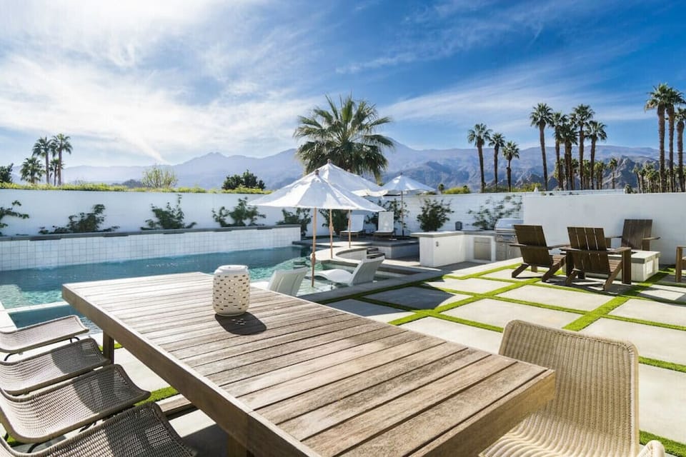 Poolside dining area w/ long table, perfect for meals under the open sky