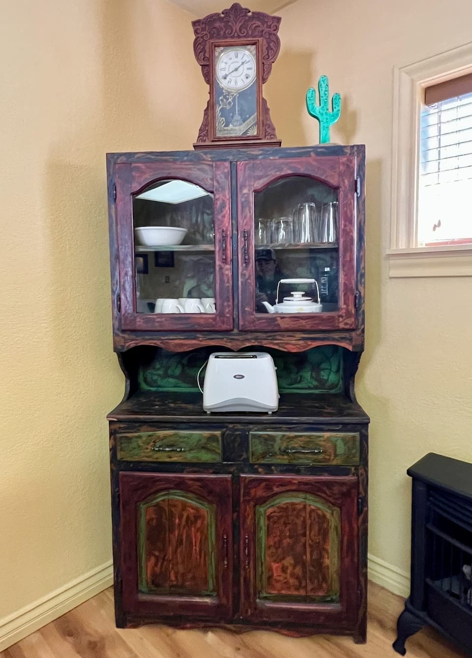 Rustic dining hutch stores dishes, glasses, coffee cups, teapot, and other kitchen/dining amenities.