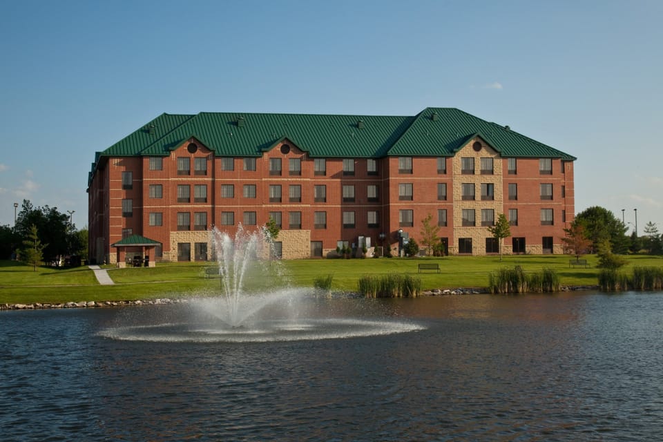 Building exterior beside a lake with fountain feature.