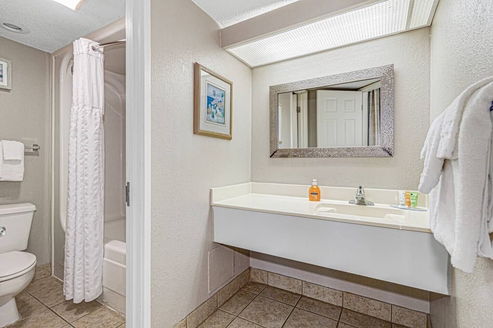 Indulge in bathtime bliss in our bathroom, where a comfortable bathtub, a contemporary sink, and a toilet create the perfect setting for relaxation.