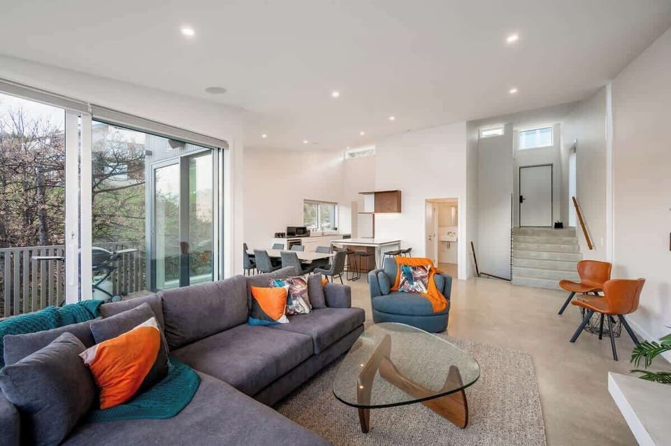 This elegant living room offers a gas fireplace, plush seating, and floor-to-ceiling windows that showcase panoramic lake and mountain views, creating a serene atmosphere for relaxation.