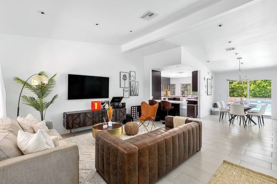Bright open-plan living, dining, and kitchen flowing toward pool-view sliders — the whole group fits and no one feels far from the action.
